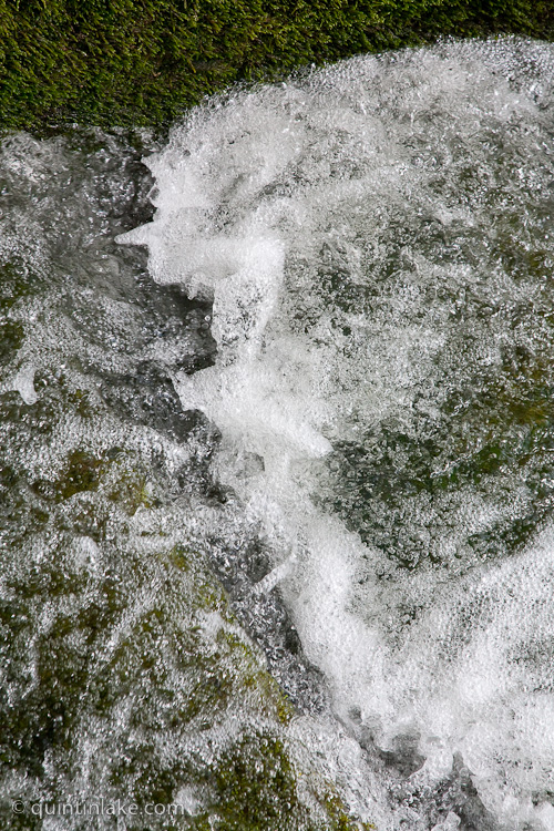Bubbling water rushes by moss at the the mill race at Skinner's Mill, Painswick